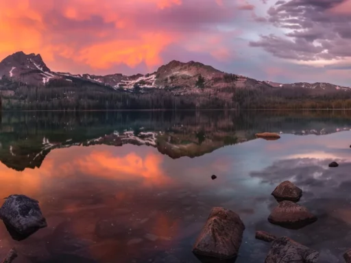 a breathtaking sunset casts a warm golden glow over a tranquil lake, reflecting the vibrant hues of orange, pink, and purple clouds above, creating a serene and harmonious atmosphere.