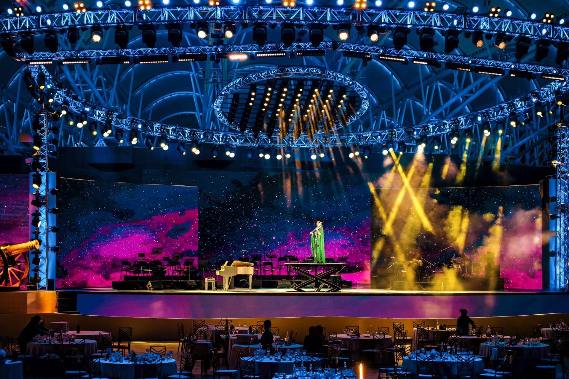 A performer plays piano on a brightly lit stage