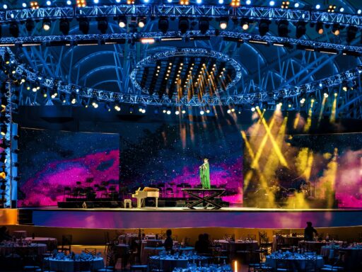 A performer plays piano on a brightly lit stage