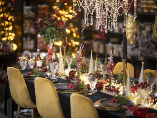 A holiday dinner table set with candles, gold chairs and warm lights.