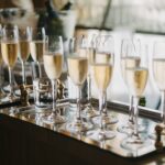Glasses of sparkling wine lined up on a tray at a reception.