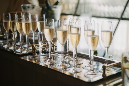 Glasses of sparkling wine lined up on a tray at a reception.