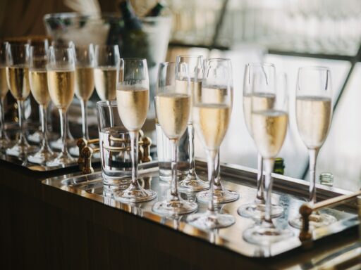 Glasses of sparkling wine lined up on a tray at a reception.