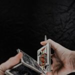Person holding playing cards on black textile