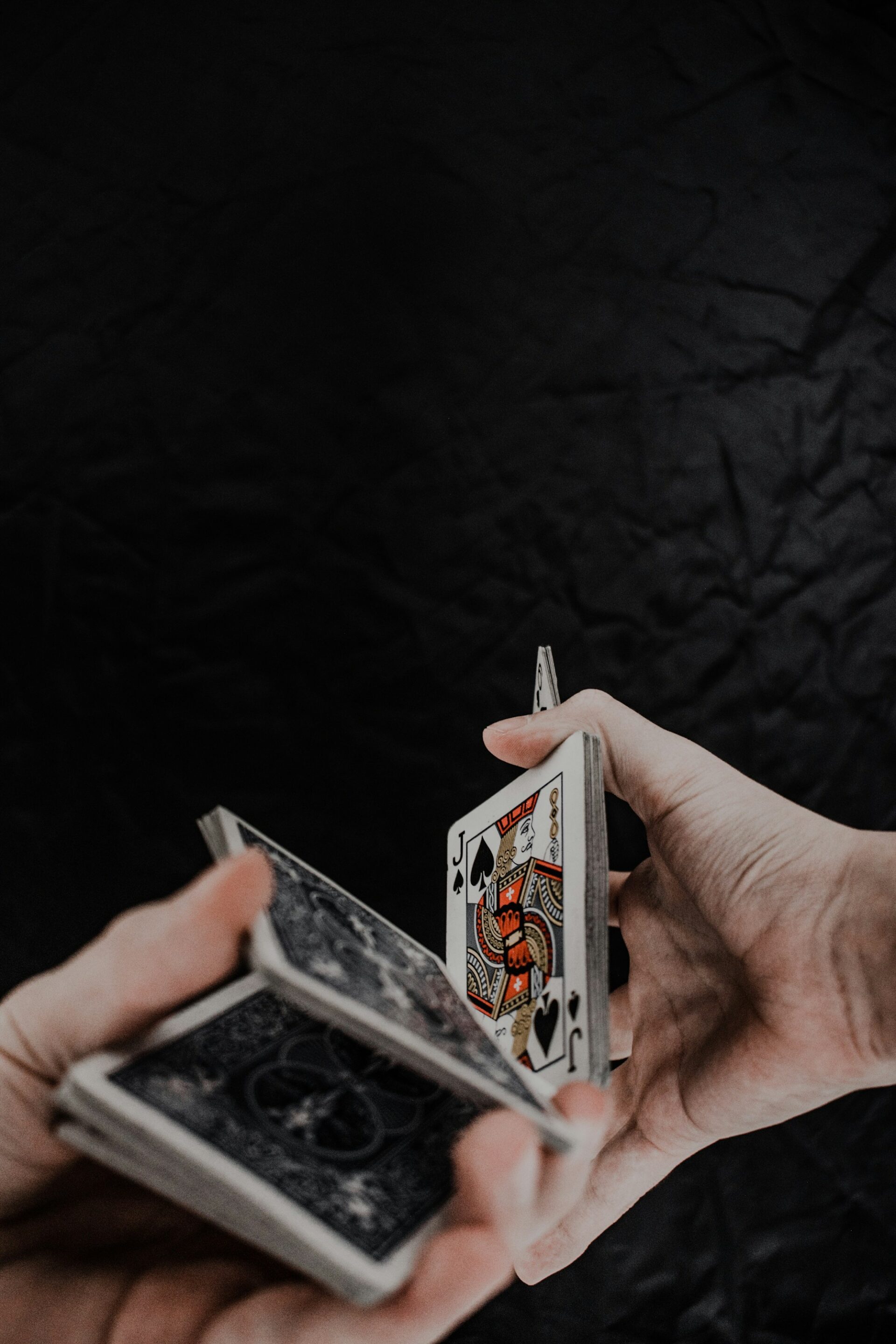 Person holding playing cards on black textile