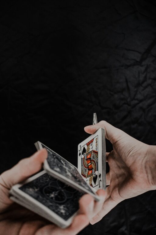 Person holding playing cards on black textile