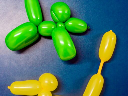 Two balloon animals, one green and one yellow, on a blue background.