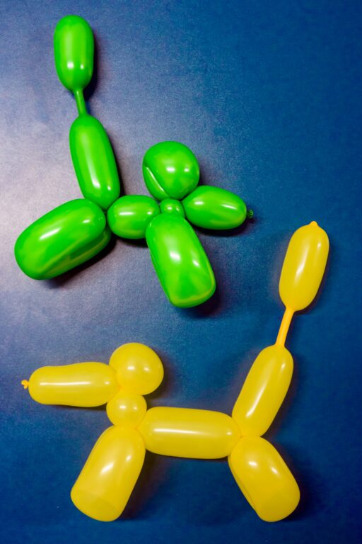 Two balloon animals, one green and one yellow, on a blue background.