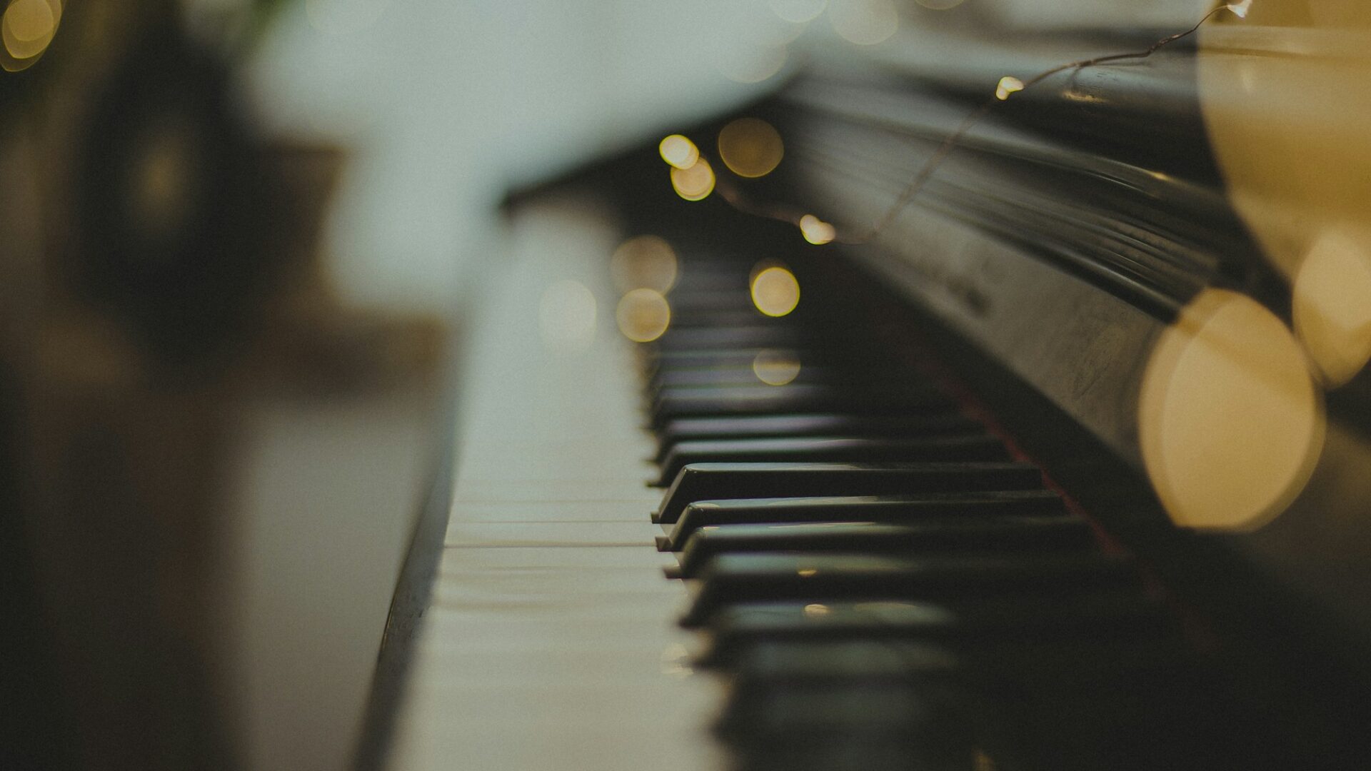 Close-up of piano keys with soft, warm lights behind them.