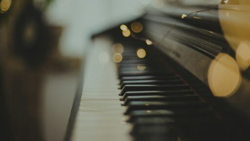 Close-up of piano keys with soft, warm lights behind them.