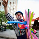 Children's party entertainer twisting balloon animals outdoors