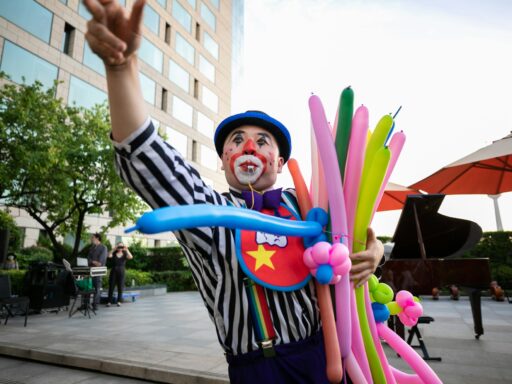 Children's party entertainer twisting balloon animals outdoors