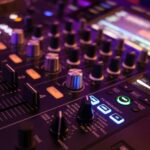A DJ's sound board with lit-up buttons and knobs