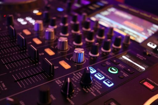 A DJ's sound board with lit-up buttons and knobs