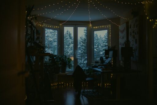 A room lit by fairy lights, with snowy trees outside the windows.