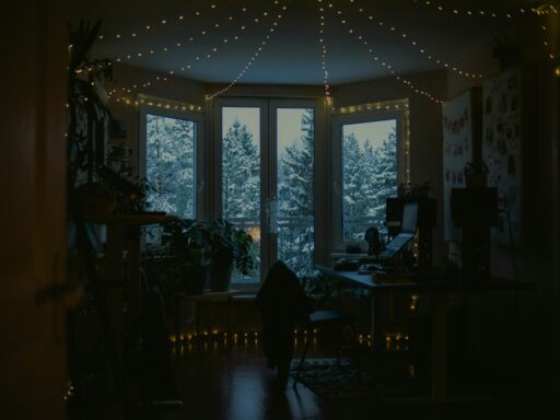 A room lit by fairy lights, with snowy trees outside the windows.