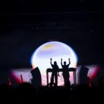 Silhouettes of people behind a DJ console