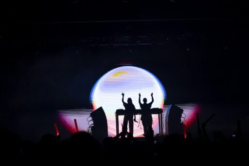 Silhouettes of people behind a DJ console