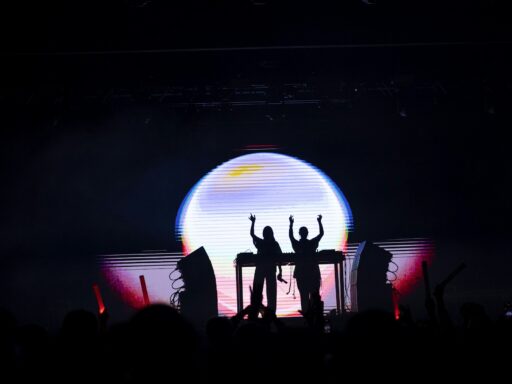 Silhouettes of people behind a DJ console