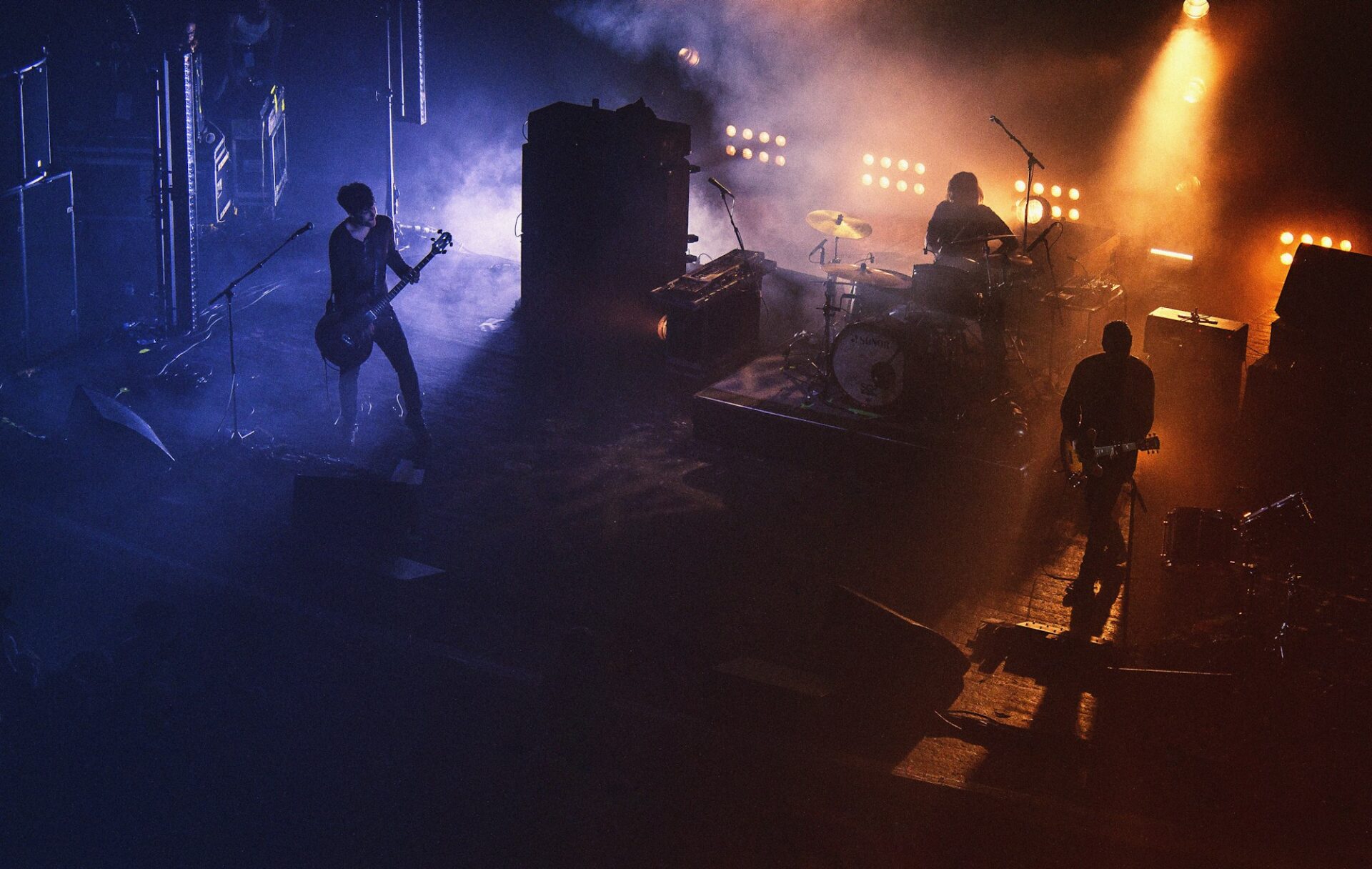 Three people playing assorted instruments on stage