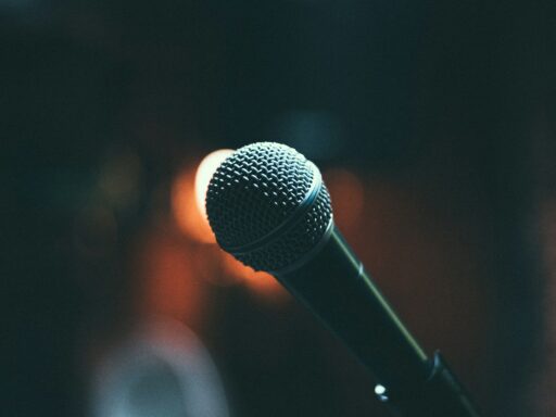A close-up of a microphone with a warm, blurred stage light behind it.