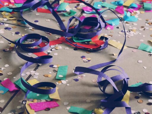 Paper streamers and coloured confetti scattered across a floor after a party.