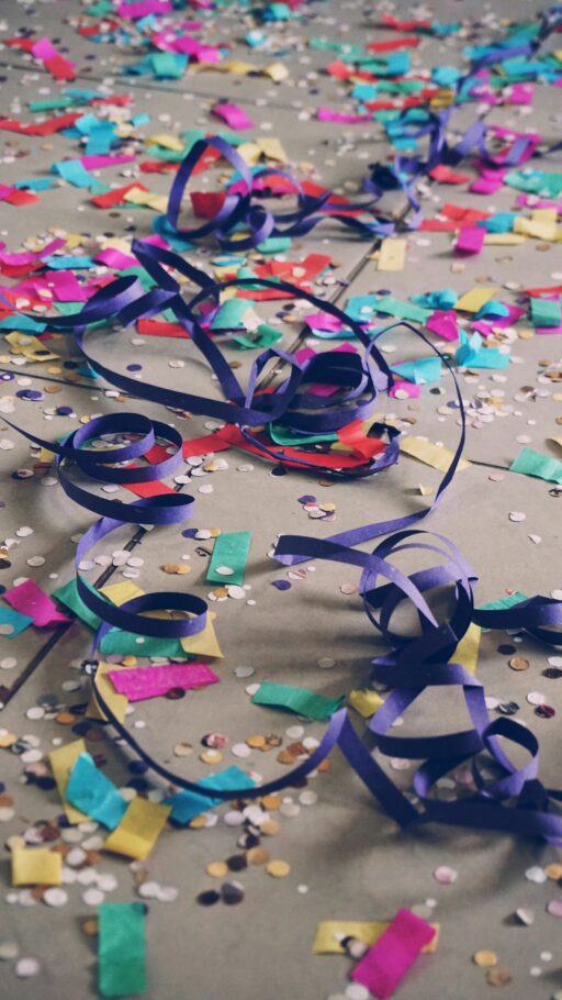 Paper streamers and coloured confetti scattered across a floor after a party.