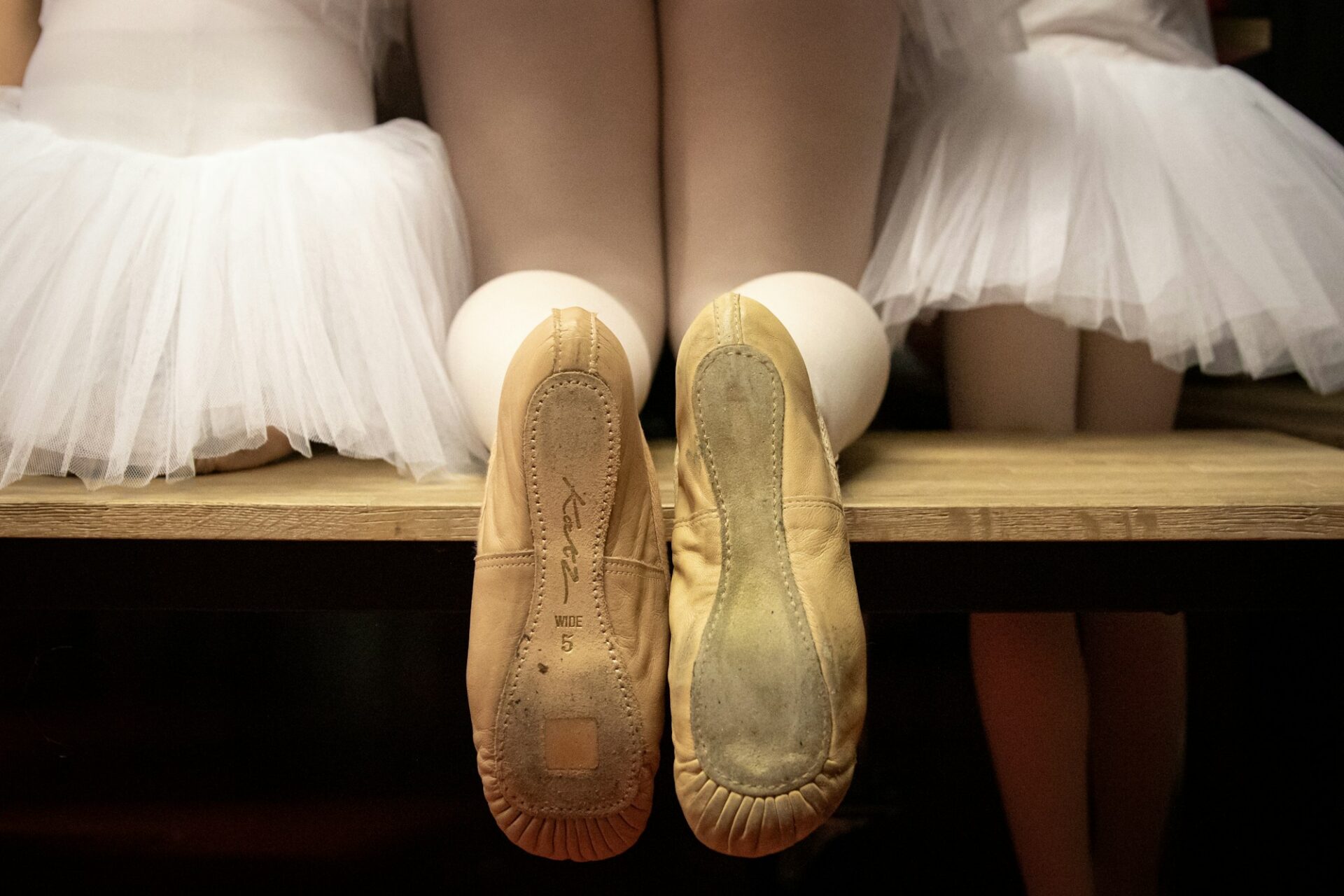 A pair of ballet shoes on a wooden shelf